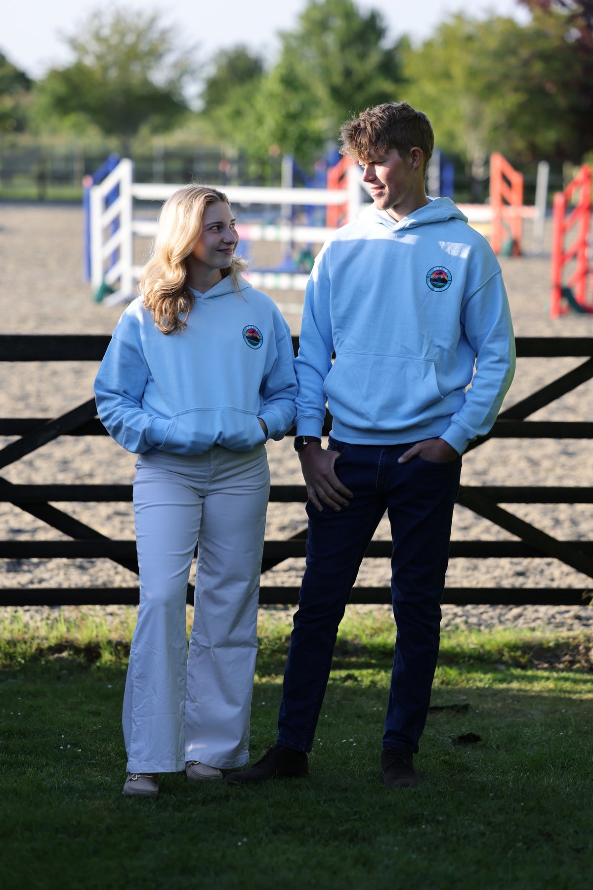 A man and a woman wearing matching oversized light blue Equestrian hoodies.