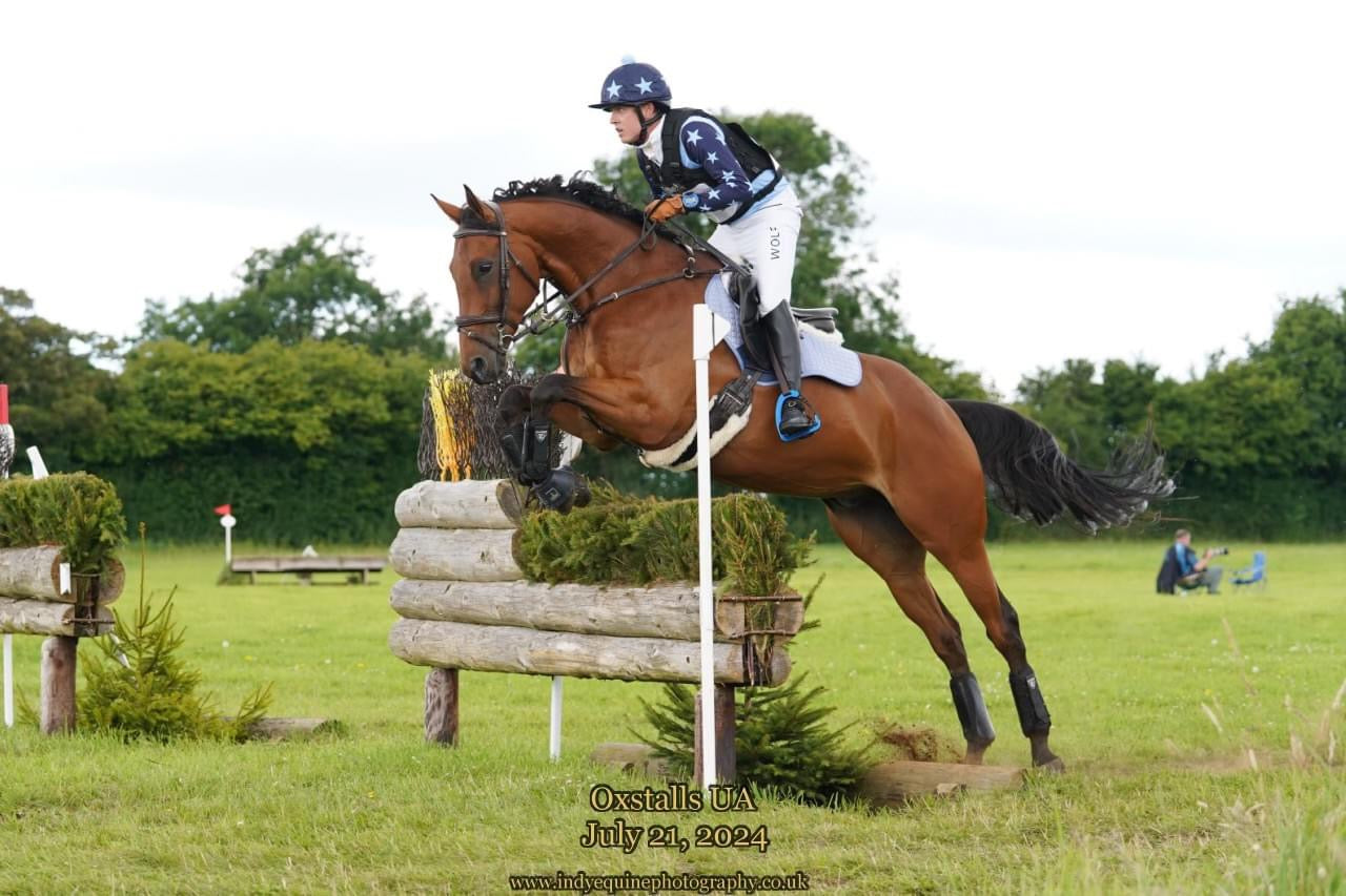 Men's White Competition Breeches in action while eventing over a XC jump on a horse. 