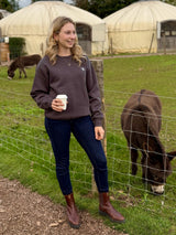 A Women wearing Unisex Wolf London Fleece Jumper stood next to Donkeys 